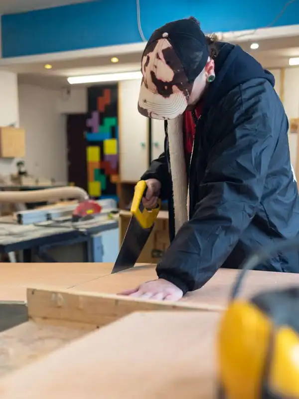 Handcrafted trainee sawing wood in a workshop