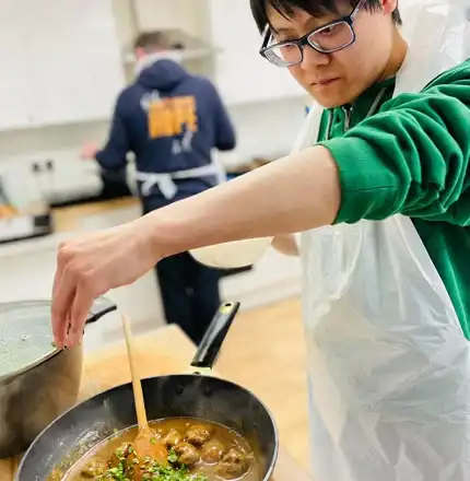 A trainee cooking a meal in the Handcrafted kitchen