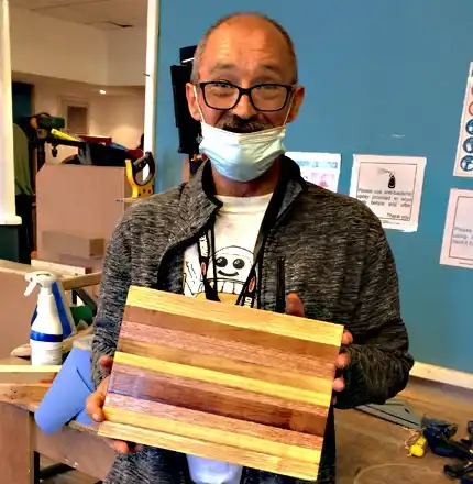 A trainee proudly showing his completed woodwork project